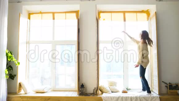 阳光明媚的一天年轻女子在卧室的窗户上跳舞视频的预览图