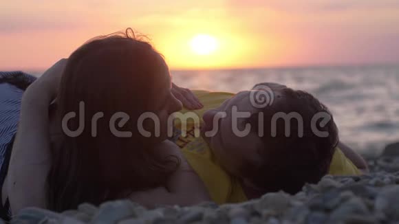 恋爱中的情侣浪漫地躺在阳光下一起慢镜头地看着日落时微笑的镜头视频的预览图