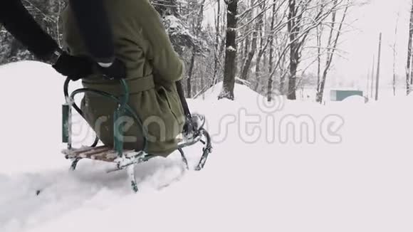 在阳光明媚的冬日里年轻的夫妇滑着雪橇享受着快乐慢动作视频的预览图