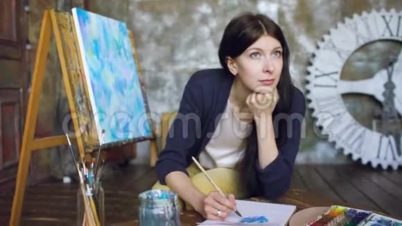 年轻的女艺术家用水彩画和微笑在窗户上画画视频的预览图