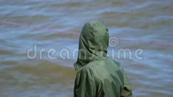 小男孩是一个十几岁的孩子穿着一件灰绿色的夹克站在湖边享受着清新的微风他转身视频的预览图