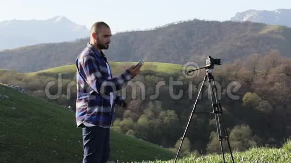 摄影师用手机在山上景观拍照视频的预览图
