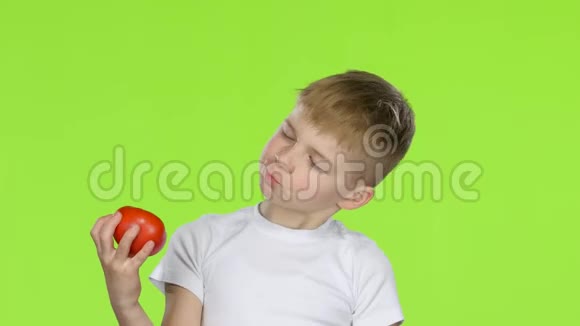 小男孩拿着番茄嗅着它竖起大拇指绿色屏幕视频的预览图