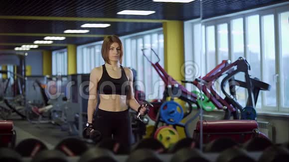一位成年女运动员在健身俱乐部里手臂上摆动着二头肌视频的预览图