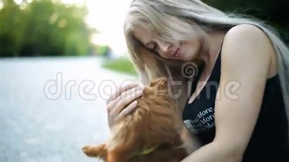 一位金发碧眼的金发女人玩着波美拉尼亚斯皮茨犬种的狗关怀微笑视频的预览图
