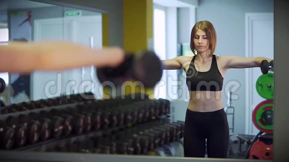 一个女人用尖锐的动作举起手臂用哑铃做运动视频的预览图