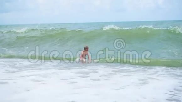 阳光明媚的一天快乐的孩子在海浪中洗澡视频的预览图