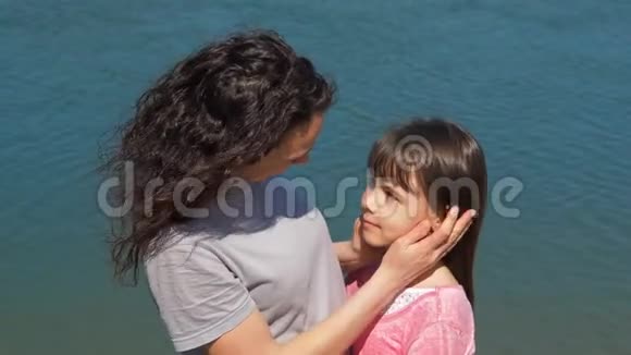 妈妈在河边拥抱她的女儿一个小女孩和她妈妈在水边家庭在露天视频的预览图