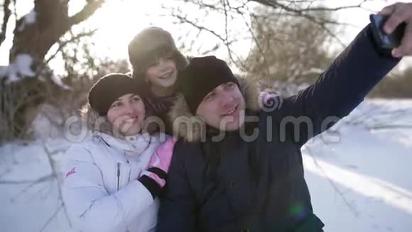 快乐的年轻家庭制作自拍智能手机妈妈爸爸和儿子寒冷晴朗的冬日视频的预览图