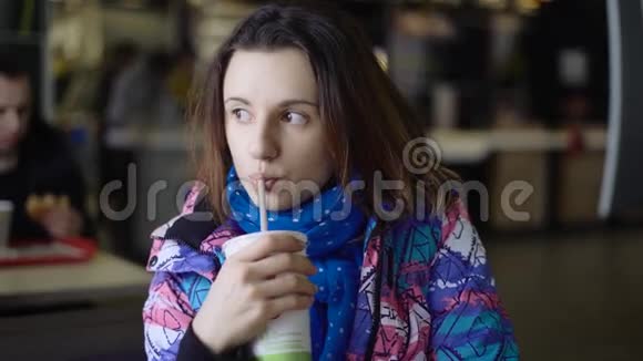 女孩从街上跑进咖啡馆很快就会吃东西黑发女人穿着运动夹克喝着一杯视频的预览图