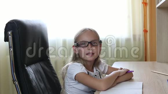 戴眼镜的年轻白种人女孩坐在桌子旁的椅子上印第安人在戴眼镜的漂亮女孩上近景白色视频的预览图