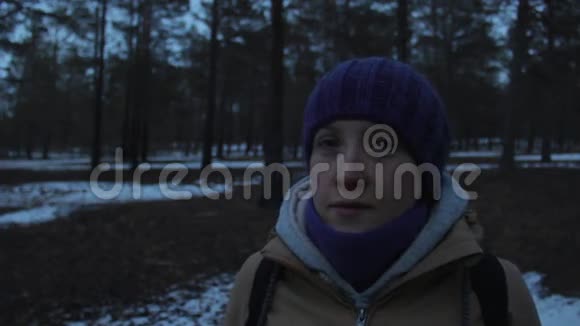 女孩在寒冷黑暗的冬日森林里四处张望视频的预览图