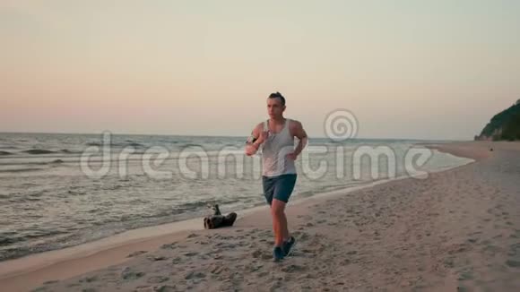 男子正在与电话慢跑在海上海岸的日落在海滩的夏季视频的预览图