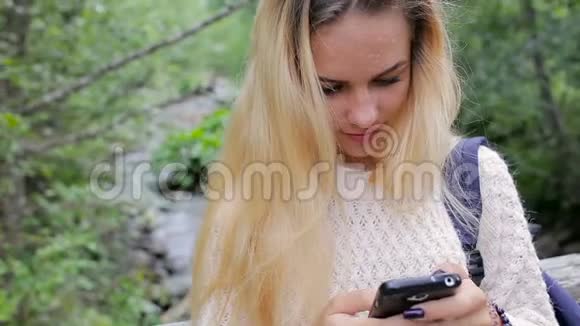 一个年轻女孩在一条山河上的桥上打电话视频的预览图