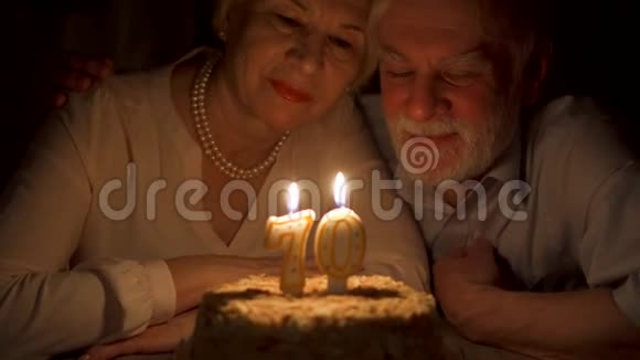 爱的老夫妇庆祝70周年与蛋糕在家里晚上吹灭蜡烛视频的预览图