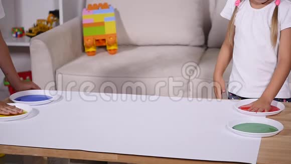 一个女孩和一个男孩在纸上留下手印动作缓慢视频的预览图