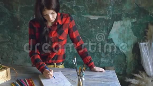 年轻的女画家用铅笔在纸笔记本上画一幅画视频的预览图