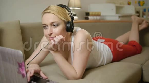 美丽的女人在skype上聊天躺在沙发上视频的预览图