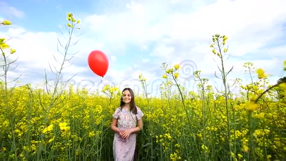 快乐的小女孩在白天在路上玩耍她站在田野里手里拿着手提箱和气球视频的预览图