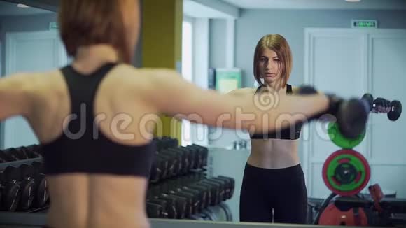 一个女人用尖锐的动作举起手臂用哑铃做运动视频的预览图