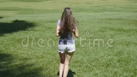 快乐的女孩正沿着乡间的绿草奔跑举手年轻漂亮的女人慢跑和旋转视频的预览图