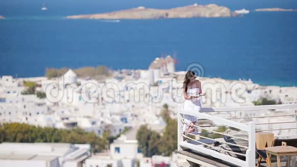 美丽的年轻女子在游泳池附近放松带着丰富的酒店的书籍在希腊的Mykonos有令人惊叹的景色视频的预览图