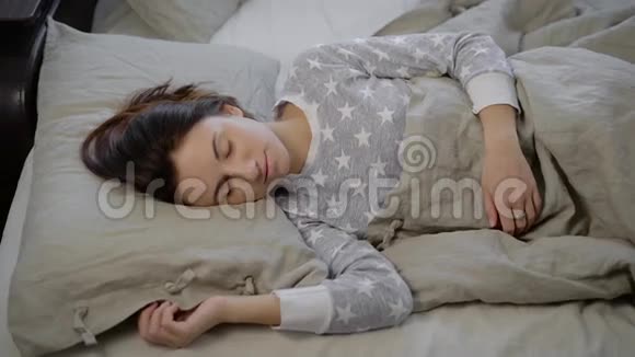 在床上的女孩那个年轻的黑发女人下午睡觉穿着灰色睡衣带星号的女人一个黑发女人视频的预览图