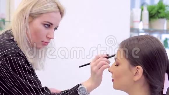 化妆师用刷子把粉涂在模特的脸上视频的预览图