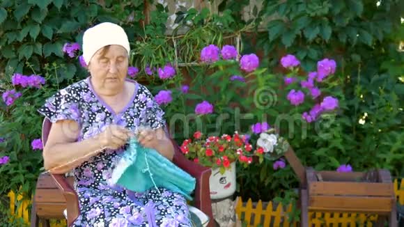 坐在他家外面大街上编织衣服的老妇人视频的预览图