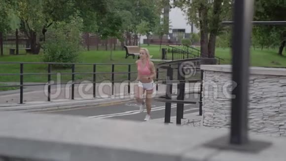 日出时英俊的女人在公园里奔跑的肖像视频的预览图