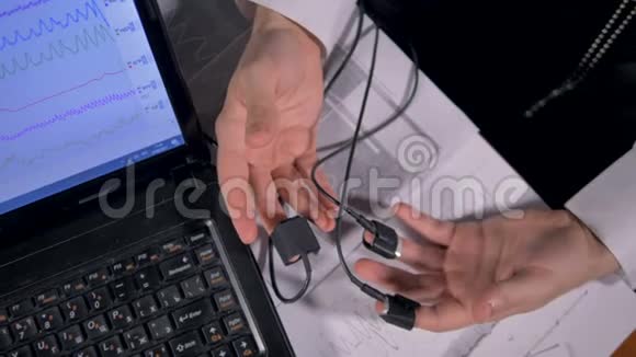 男性手在笔记本电脑屏幕旁边的打印输出上摇动视频的预览图