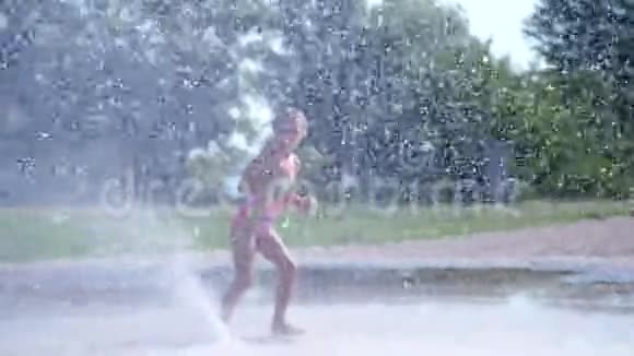 七岁的快乐女孩穿着泳衣在喷水池里嬉戏城市里阳光明媚的夏日视频的预览图