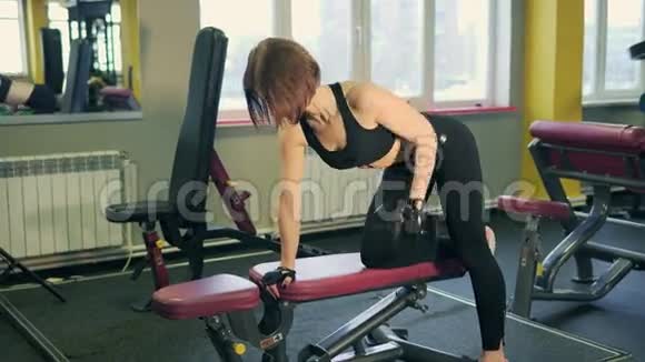 妇女做背部锻炼使用哑铃休息在膝盖和手视频的预览图