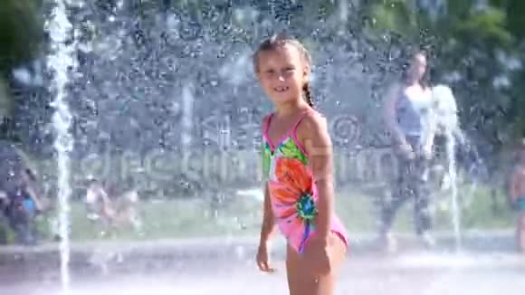 七岁的快乐女孩穿着泳衣在喷水池里嬉戏城市里阳光明媚的夏日视频的预览图