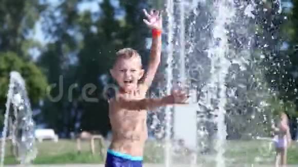 可爱的孩子一个七岁的男孩在炎热的夏天在喷泉里洗澡在外面玩水视频的预览图