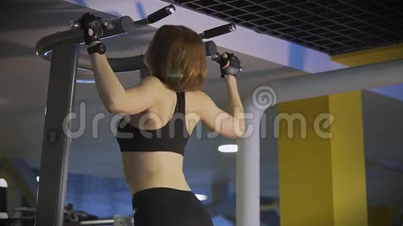 在体育俱乐部里一个运动女人确实把整个身体都拉在横梁上视频的预览图