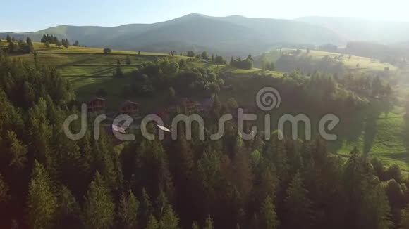 木制的农舍矗立在群山之间的森林后面视频的预览图
