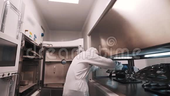 穿着长袍和橡胶手套的工程师在实验室将金属元素放入烤箱视频的预览图