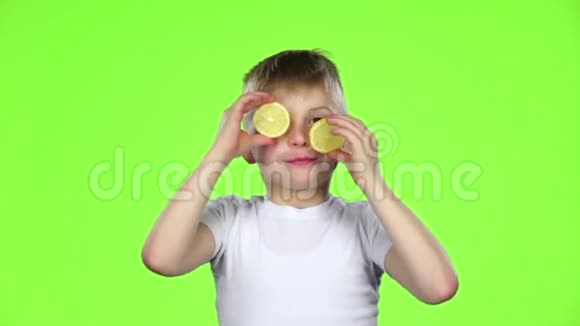 小男孩拿着几片柠檬舔它们露出鬼脸绿色屏幕慢动作视频的预览图