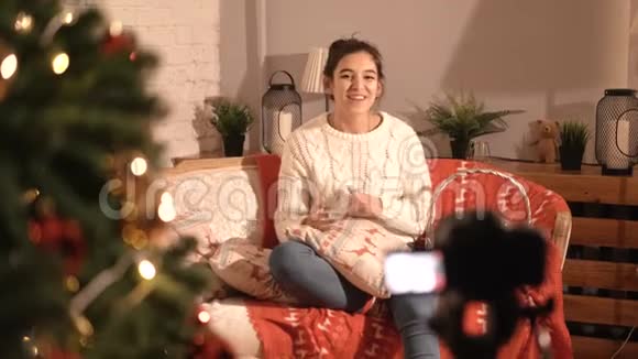 女博客坐在家里的沙发上谈论新年和圣诞节视频的预览图