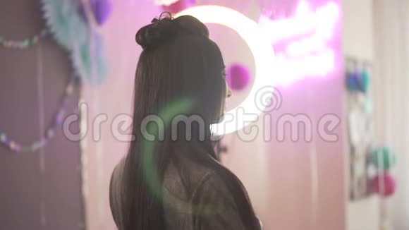 美丽迷人的年轻黑发女郎拿着粉色的装饰球在镜头前转身微笑视频的预览图