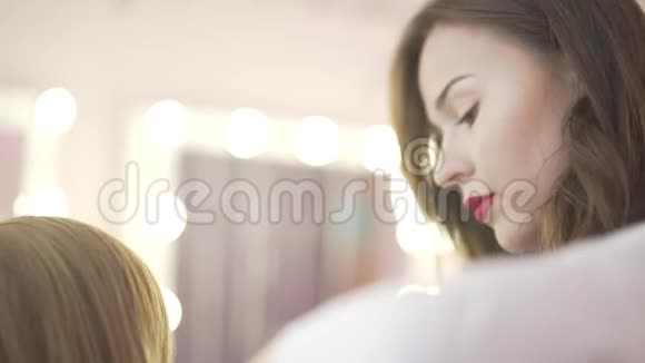 年轻漂亮的女美发师造型师精心刷金发模特做专业沙龙发型视频的预览图
