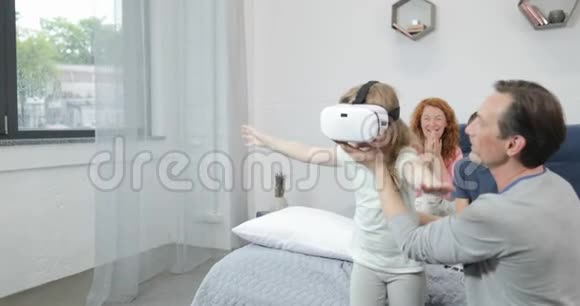 女儿尝试虚拟现实眼镜与父亲在卧室家庭上午一起在家视频的预览图
