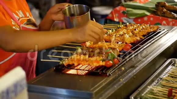 亚洲街头美食卖家在柜台上用蔬菜做成的木串上烤串视频的预览图