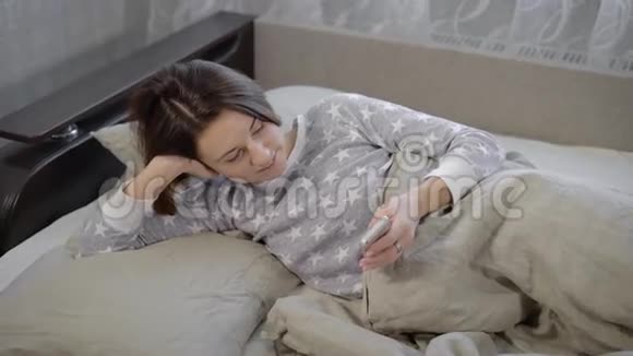 黑短发的青少年穿着灰色睡衣躺在床上看着手机上的各种网站她是视频的预览图