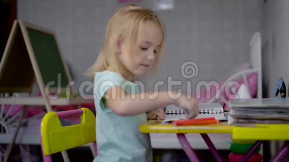 小女孩坐在桌子旁用铅笔画画小孩正在学画画视频的预览图