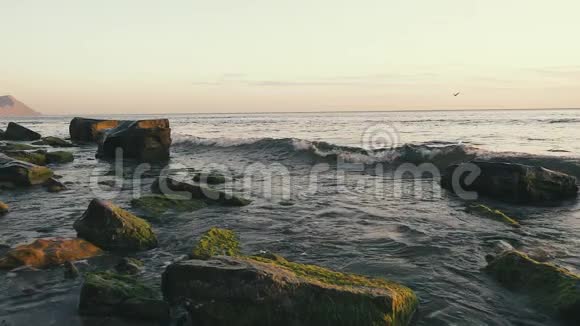 日落时分波浪在水中的巨石上飞溅视频的预览图