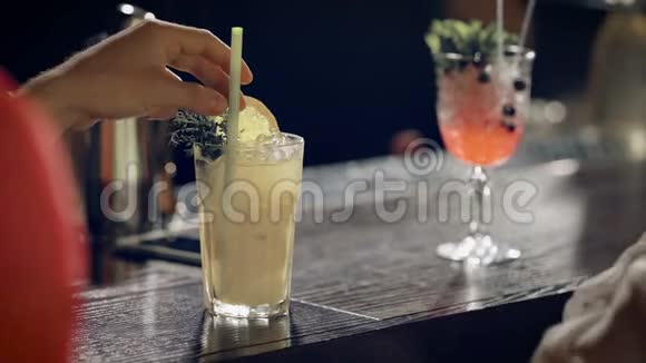 酒吧里摆着一杯含酒精饮料的酒杯一个男人手在鸡尾酒里转动一根管子视频的预览图