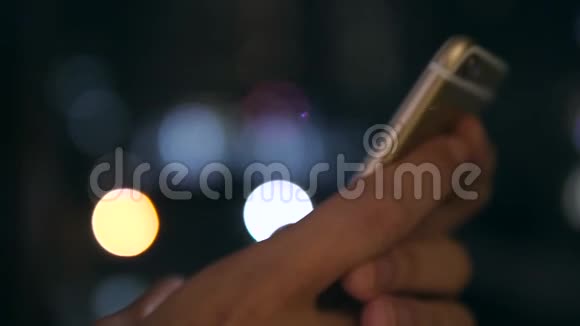 女性手使用智能手机与模糊的蓝色博克街城市夜路灯光背景4K泰国曼谷视频的预览图