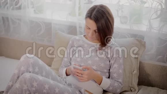 一个黑发的年轻女孩穿着睡衣坐在床上在你休息的一天里和一个人一起覆盖着星星视频的预览图